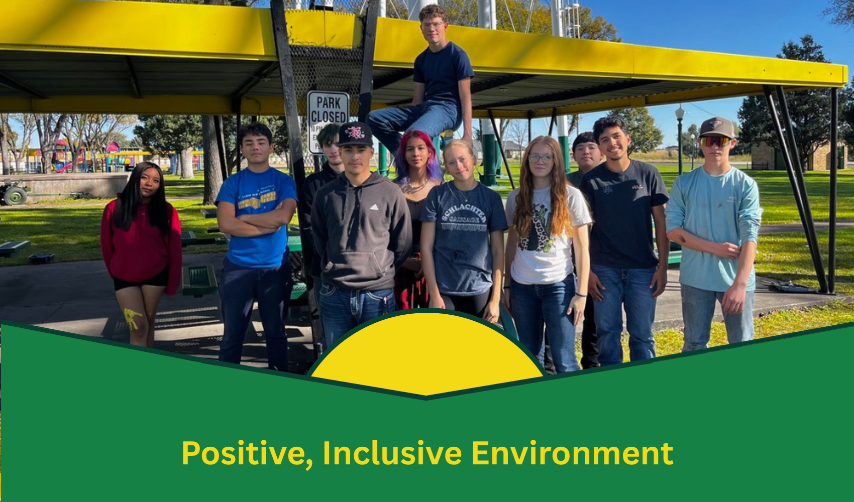A group of young people standing under a yellow canopy in a park with a text banner below.

Transcribed Text:

Positive, Inclusive Environment
